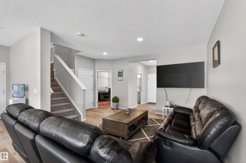 Open-concept living space with light gray walls, wood-finish flooring, recessed lighting, and a staircase with neutral carpeting and a white railing - 22638 99A Avenue, Edmonton, AB - Indoor Photo Showing Living Room