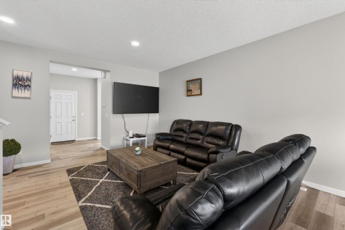 Open living area featuring wood-finish flooring, light gray wall tones, recessed lighting, and a white paneled entry door - 22638 99A Avenue, Edmonton, AB - Indoor Photo Showing Living Room