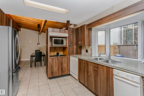 The kitchen features wood cabinetry, a double basin sink, and a bay window - 24 Sable Crescent, St. Albert, AB - Indoor Photo Showing Kitchen With Double Sink