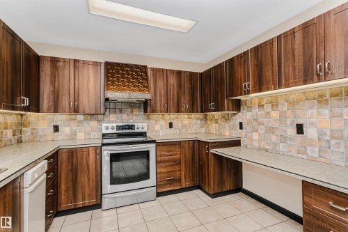 The kitchen features extensive wood cabinetry, a stainless steel range, and a tiled backsplash - 24 Sable Crescent, St. Albert, AB - Indoor Photo Showing Kitchen