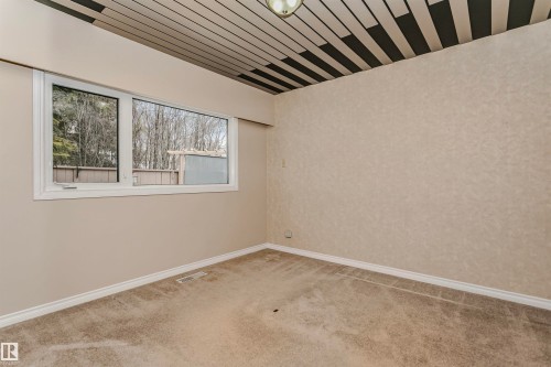 This room features a window providing views of trees and a building in the distance, neutral-toned walls, and a patterned ceiling - 24 Sable Crescent, St. Albert, AB - Indoor Photo Showing Other Room