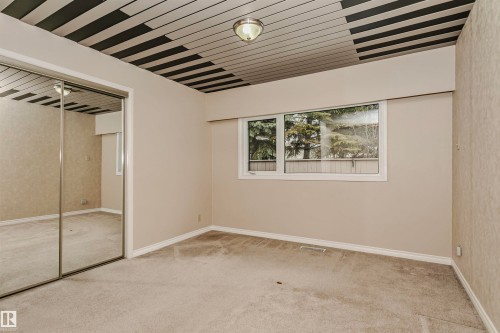 The property features a room with carpeted flooring, a window offering views of trees, and a ceiling light fixture - 24 Sable Crescent, St. Albert, AB - Indoor Photo Showing Other Room