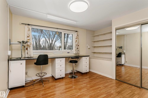 This versatile room features warm-toned flooring, a built-in desk with storage, and integrated shelving - 24 Sable Crescent, St. Albert, AB - Indoor Photo Showing Office