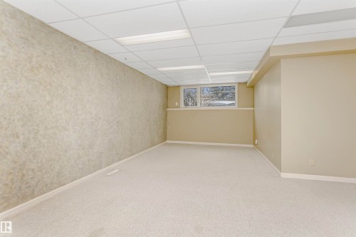 Spacious room featuring light-colored carpeting, a drop ceiling with integrated lighting, and windows providing natural light - 24 Sable Crescent, St. Albert, AB - Indoor Photo Showing Other Room