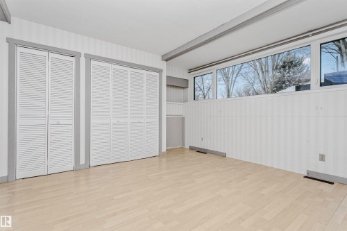 This room features light-colored flooring, windows, and two white louvered bifold closet doors - 24 Sable Crescent, St. Albert, AB - Indoor Photo Showing Other Room