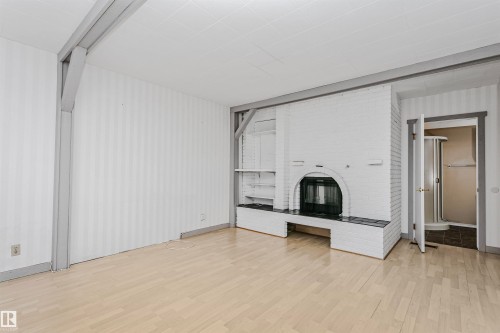 Spacious room featuring light-colored flooring, a white brick fireplace with a dark-toned hearth, and built-in shelving - 24 Sable Crescent, St. Albert, AB - Indoor