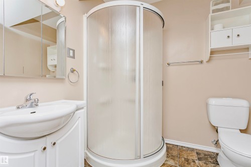 The bathroom features a curved, enclosed shower, a white vanity with a ceramic sink, and a toilet - 24 Sable Crescent, St. Albert, AB - Indoor Photo Showing Bathroom