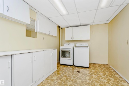 Laundry area featuring ample white cabinetry for storage, a washer, a dryer, and a neutral-toned tiled floor - 24 Sable Crescent, St. Albert, AB - Indoor Photo Showing Laundry Room