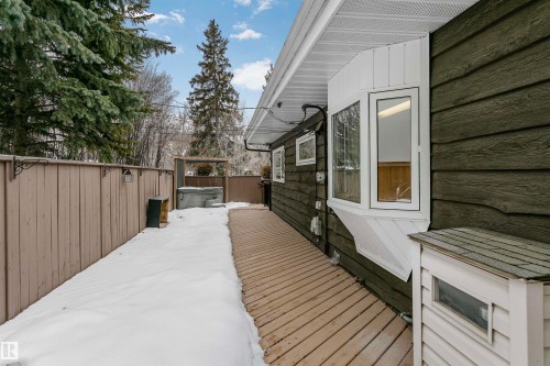The property features dark green horizontal siding, a light wood fence, and a wooden deck - 24 Sable Crescent, St. Albert, AB - Outdoor With Exterior