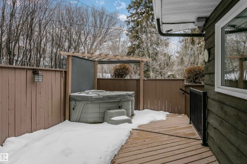 This property features a private deck with a hot tub, partially covered by a pergola, and surrounded by a wooden fence - 24 Sable Crescent, St. Albert, AB - Outdoor With Exterior