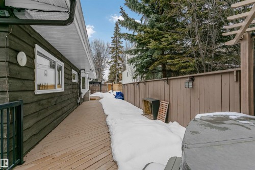 Exterior view of the property featuring a wood-sided wall with white-framed windows, an extensive wooden deck, and a privacy fence - 24 Sable Crescent, St. Albert, AB - Outdoor With Exterior
