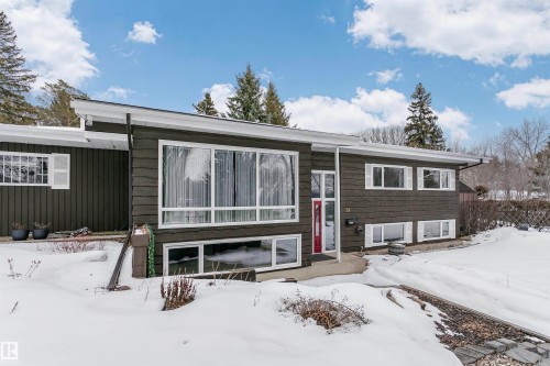 The property features a dark exterior with white window frames and white shutters, complemented by a prominent red front door - 24 Sable Crescent, St. Albert, AB - Outdoor