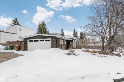 The property features a dark-colored exterior, a white garage door with windows, and a partially visible fence - 24 Sable Crescent, St. Albert, AB - Outdoor