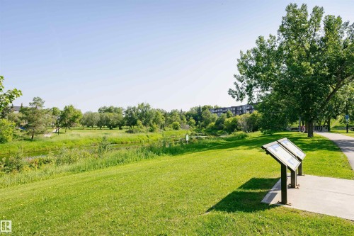 The community features extensive green spaces, a paved pathway, mature trees, and a visible water feature - 24 Sable Crescent, St. Albert, AB - Outdoor With View