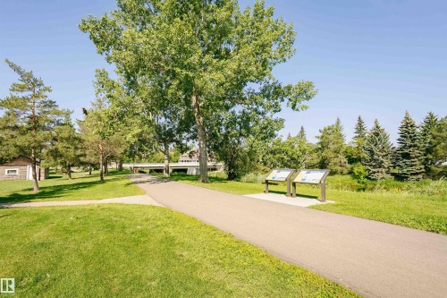 The property is situated within a green space featuring a paved pathway, mature trees, and well-maintained grassy areas - 24 Sable Crescent, St. Albert, AB - Outdoor With View