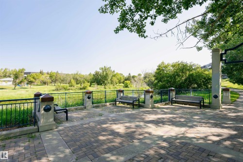 Paved communal area featuring two benches, a metal fence, and views of a verdant landscape with mature trees - 24 Sable Crescent, St. Albert, AB - Outdoor