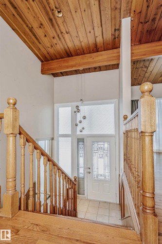 Entryway featuring a wooden staircase with balusters and a wooden handrail, leading to a front door with decorative glass panels and a transom window - 24 Sable Crescent, St. Albert, AB - Indoor Photo Showing Other Room