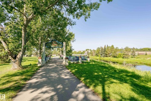 The property offers a paved pathway surrounded by mature trees and extensive green spaces - 24 Sable Crescent, St. Albert, AB - Outdoor With View