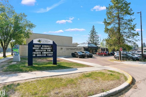 The neighborhood features a community elementary school with a prominent sign, an adjacent parking lot, and mature trees surrounding the building - 24 Sable Crescent, St. Albert, AB - Outdoor