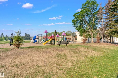 Community playground featuring a colorful play structure with slides and a bench for seating - 24 Sable Crescent, St. Albert, AB - Outdoor