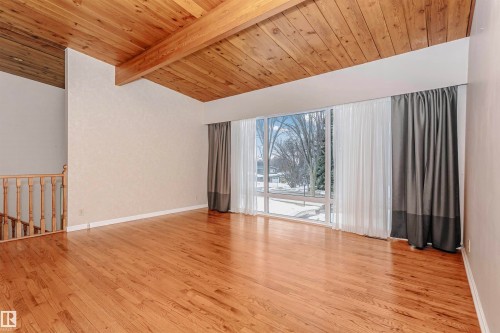 The property features hardwood flooring, a wood-paneled ceiling with exposed beams, and a large window providing views of the outdoors - 24 Sable Crescent, St. Albert, AB - Indoor Photo Showing Other Room
