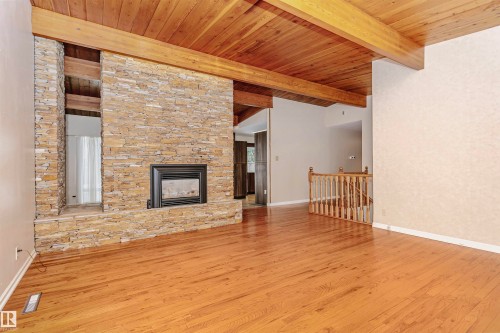 Living area featuring hardwood floors, a stone fireplace, and a wood-beamed ceiling - 24 Sable Crescent, St. Albert, AB - Indoor With Fireplace