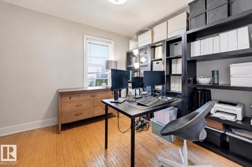Room featuring wood-finish flooring, a double-hung window, and extensive built-in shelving - 9816 93 Avenue, Edmonton, AB - Indoor Photo Showing Office
