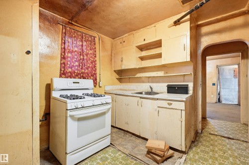 Kitchen area featuring a freestanding range, built-in cabinetry, a single basin sink, and an arched doorway - 9816 93 Avenue, Edmonton, AB - Indoor Photo Showing Kitchen