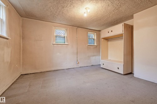 Room featuring a built-in wardrobe with upper cabinetry and lower drawers, two casement windows with security screens, and a ceiling-mounted light fixture - 9816 93 Avenue, Edmonton, AB - Indoor Photo Showing Other Room