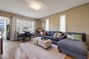 Living area featuring wood-finish flooring, a contemporary ceiling light fixture, and multiple windows with natural light - 9816 93 Avenue, Edmonton, AB  - Indoor Photo Showing Living Room 