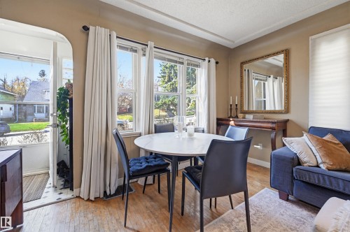 Living area featuring wood-finish flooring, multiple windows providing natural light, and a white ceiling with decorative trim - 9816 93 Avenue, Edmonton, AB - Indoor Photo Showing Dining Room