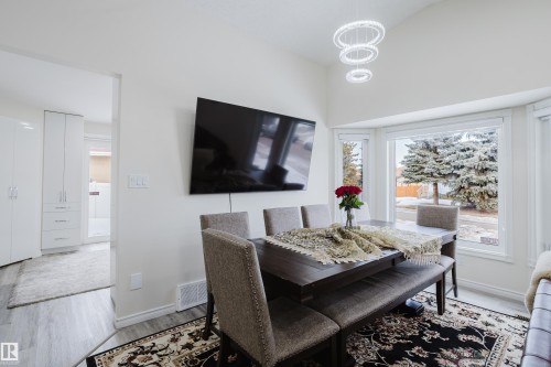 Dining area featuring a contemporary chandelier, vaulted ceiling, and bay window - 236 Lago Lindo Crescent, Edmonton, AB - Indoor Photo Showing Dining Room