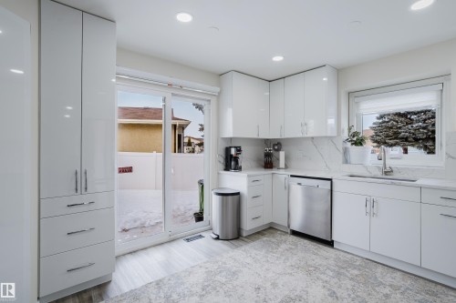 Contemporary kitchen featuring white flat-panel cabinetry, stainless steel appliances, and light-colored countertops with a matching backsplash - 236 Lago Lindo Crescent, Edmonton, AB - Indoor Photo Showing Kitchen