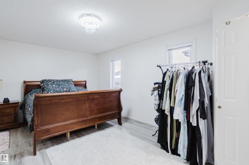 Light-filled room featuring white walls, a crystal chandelier, and wood-finish flooring - 236 Lago Lindo Crescent, Edmonton, AB - Indoor Photo Showing Bedroom