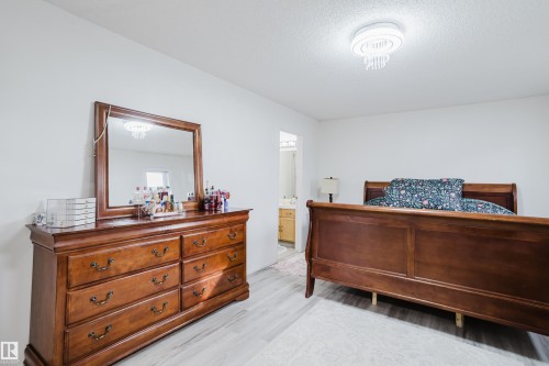 Spacious room featuring light wood-finish flooring, white walls, and a ceiling-mounted lighting fixture with decorative elements - 236 Lago Lindo Crescent, Edmonton, AB - Indoor Photo Showing Bedroom