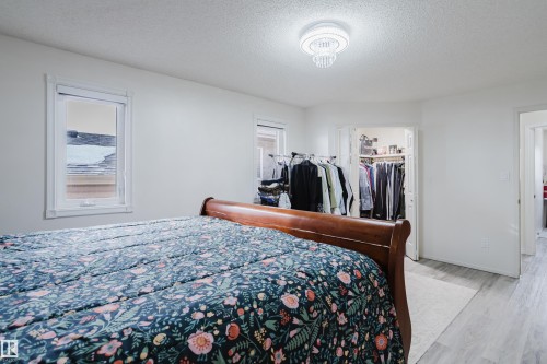 Bedroom featuring light wood-finish flooring, two windows with white trim, and a built-in closet with bifold doors - 236 Lago Lindo Crescent, Edmonton, AB - Indoor Photo Showing Bedroom