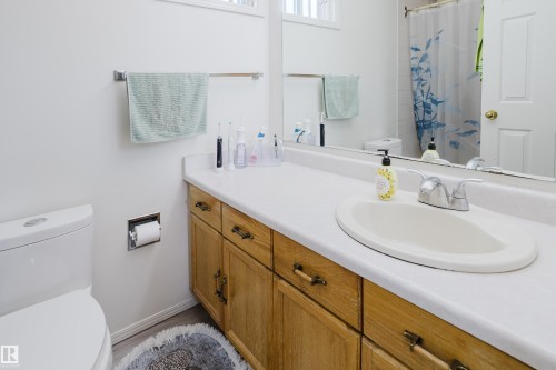 Bathroom vanity featuring a built-in sink with a chrome faucet, wood-finish cabinetry with antique-style hardware, and a large wall-mounted mirror - 236 Lago Lindo Crescent, Edmonton, AB - Indoor Photo Showing Bathroom