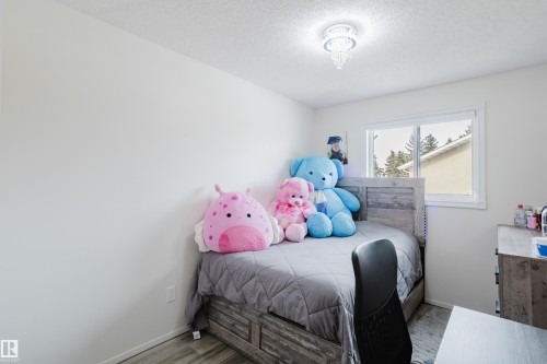Bright room featuring a window with white trim, a decorative ceiling light fixture, light-colored walls, and wood-finish flooring - 236 Lago Lindo Crescent, Edmonton, AB - Indoor Photo Showing Bedroom