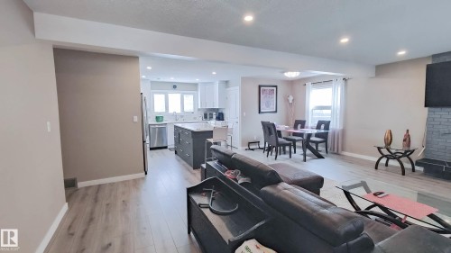 Open-concept living area featuring wood-finish flooring, recessed lighting, and a grey brick fireplace - 3311 108 Street, Edmonton, AB - Indoor Photo Showing Other Room