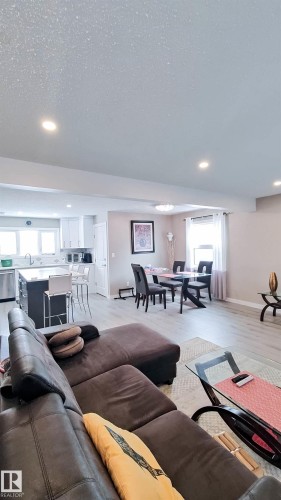 Open-concept living area featuring light wood-finish flooring, recessed ceiling lighting, and a kitchen with white cabinetry - 3311 108 Street, Edmonton, AB - Indoor Photo Showing Living Room
