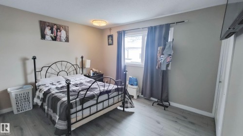 Bedroom featuring light gray walls, wood-finish flooring, a single window, and ceiling-mounted light fixture - 3311 108 Street, Edmonton, AB - Indoor Photo Showing Bedroom
