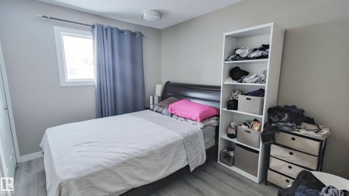 Room featuring wood-finish flooring, a white-framed window, neutral wall tones, and a ceiling-mounted light fixture - 3311 108 Street, Edmonton, AB - Indoor Photo Showing Bedroom