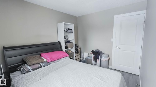 Gray wood-finish flooring, light gray wall paint, and a white interior door with contemporary hardware - 3311 108 Street, Edmonton, AB - Indoor Photo Showing Bedroom