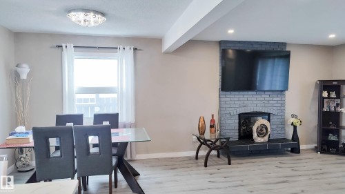 Living area featuring a gray brick fireplace with an arched firebox, recessed lighting, and light wood-finish flooring - 3311 108 Street, Edmonton, AB - Indoor With Fireplace
