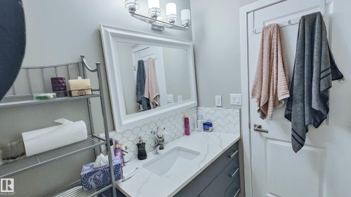 Vanity featuring a white countertop with integrated sink, modern gray cabinetry, and a white framed mirror - 3311 108 Street, Edmonton, AB - Indoor Photo Showing Bathroom