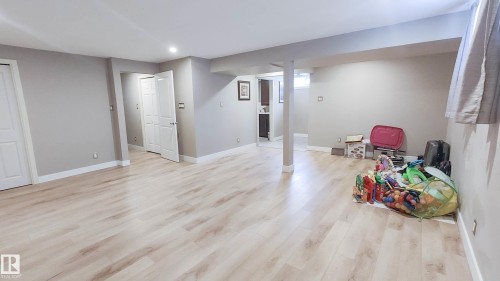 Spacious room featuring light wood-finish flooring, recessed lighting, neutral wall paint, white trim, and white paneled doors - 3311 108 Street, Edmonton, AB - Indoor