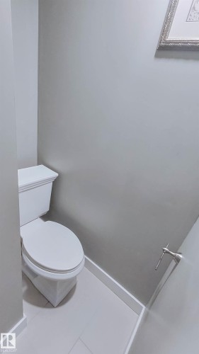 White commode with neutral wall paint, white baseboards, and light-toned tile flooring - 3311 108 Street, Edmonton, AB - Indoor Photo Showing Bathroom