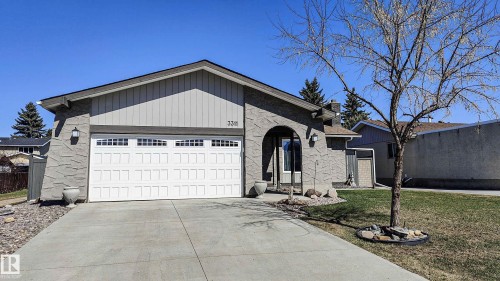 Front exterior featuring a concrete driveway, attached garage with decorative windows, and an arched entry - 3311 108 Street, Edmonton, AB - Outdoor