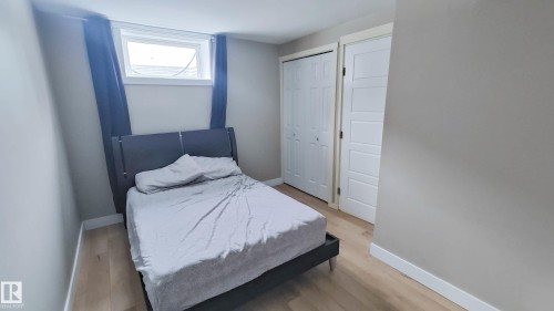 Bedroom featuring wood-finish flooring, neutral wall tones, a recessed window, and two white bi-fold closet doors - 3311 108 Street, Edmonton, AB - Indoor Photo Showing Bedroom