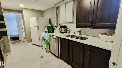 Kitchenette featuring white countertops, a double basin stainless steel sink, dark wood-finish cabinetry, and a subway tile backsplash - 3311 108 Street, Edmonton, AB - Indoor Photo Showing Kitchen With Double Sink